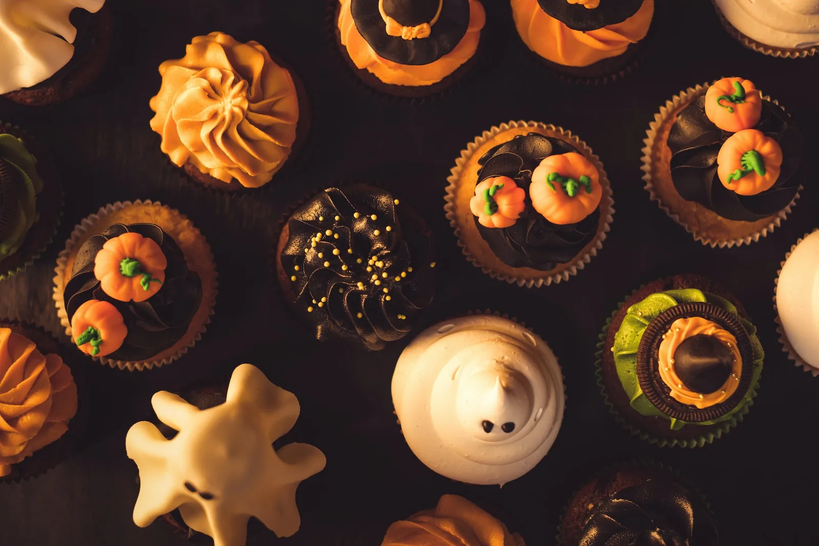 top view of traditional tasty halloween cupcakes on black